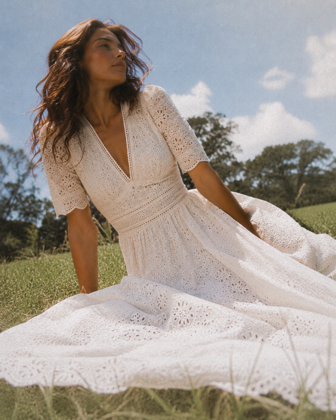 Petite model wearing an ivory eyelet dress outdoors in golden light.